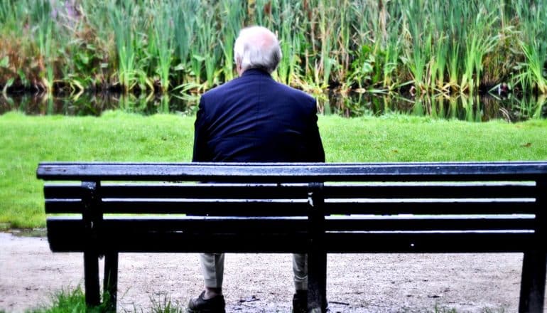 An older man sits alone on a bench