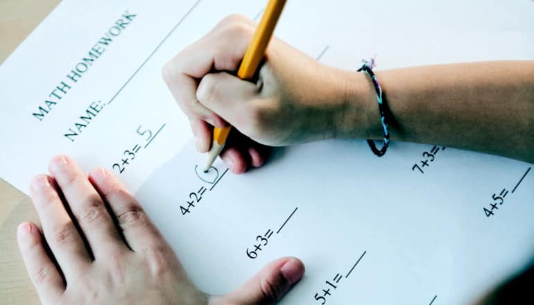 A young student does math problems with a yellow pencil