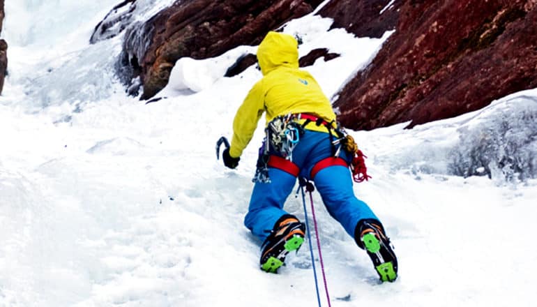 A mountain climber scales an icy, rocky surface