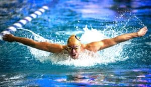 A swimmers does the butterfly stroke through the swimming pool