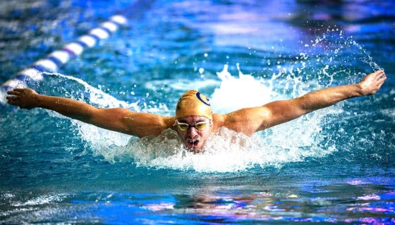 A swimmers does the butterfly stroke through the swimming pool