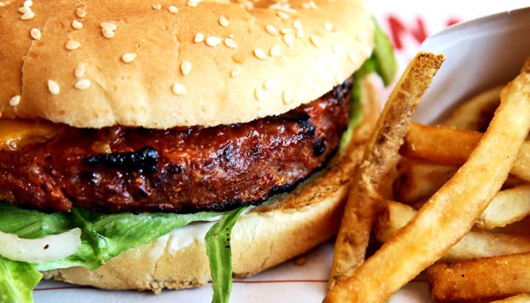 A burger made with a plant-based meat alternative next to some fries