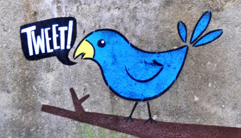 A blue bird painted on a wall saying "Tweet!"