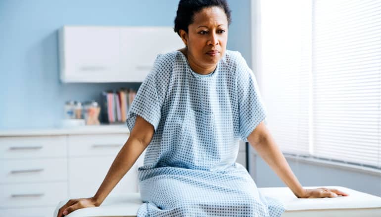 A woman sits in a doctor's office in a gown