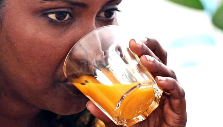 A woman drinks a glass of orange juice