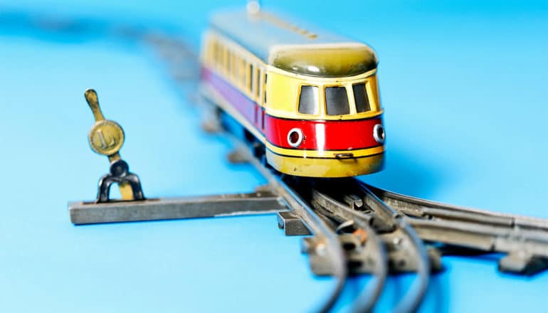 A toy train moves past a track switch and a split in the tracks