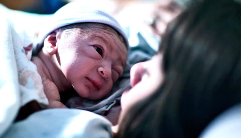 A newborn baby rests on his mother's chest in the hospital