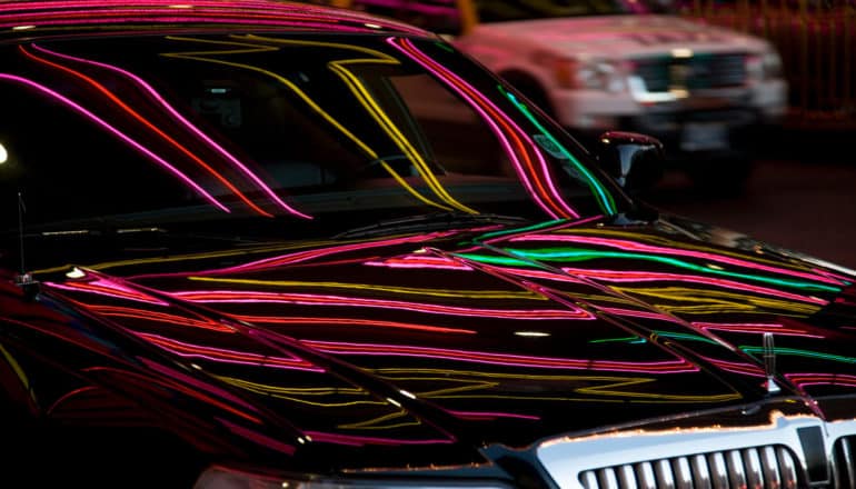 neon lights reflect on shiny black car