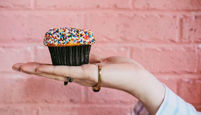 hand holds cupcake with sprinkles