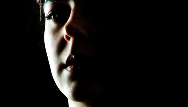 A woman's face half covered in shadow