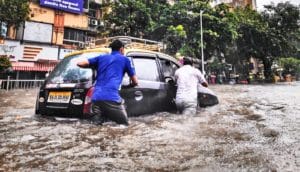 two people push car in flood water