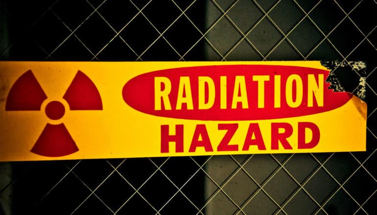 A yellow and red sign reads "Radiation Hazard" with a radiation symbol next to the text