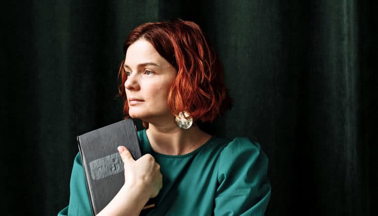 person holding book looks away thoughtfully