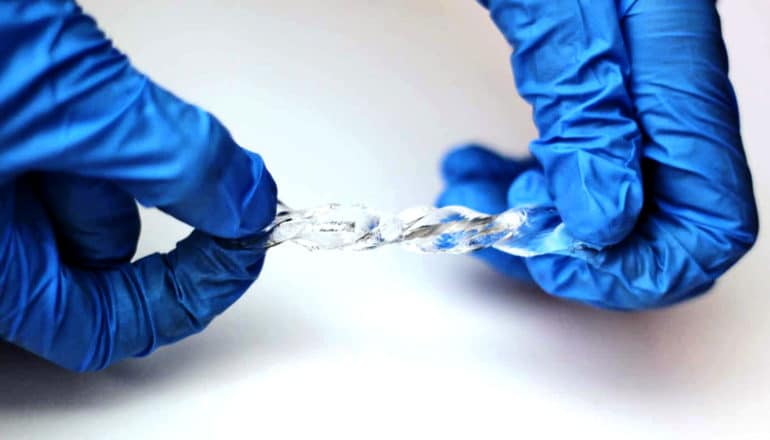 A researcher twists the clear, gel-like liquid metal