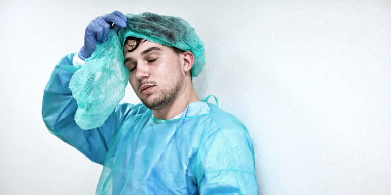 sweaty, tired person removes PPE