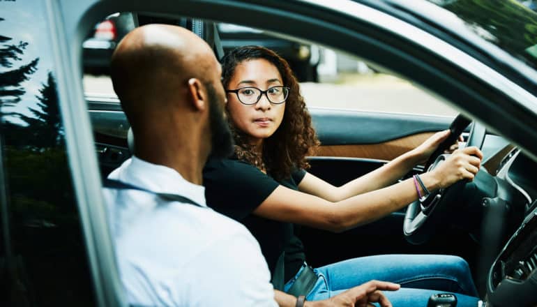 teen and adult in driver's and passenger's seats of car