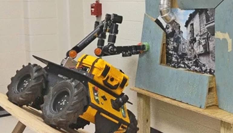 The robot sits on a tilted surface while using its arms to hold up a wall