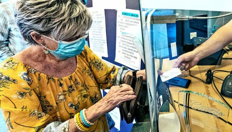 A woman hands her vaccine card to a movie theater ticket vendor