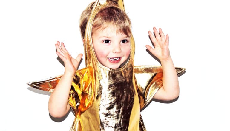 A young child in a shiny gold star costume smiles