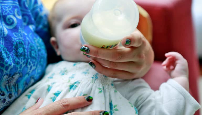 adult hands holds bottle for baby