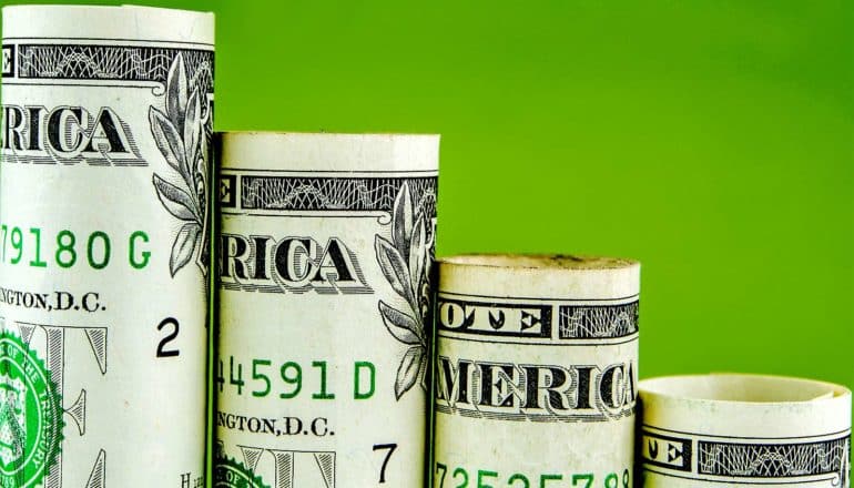 Dollar bills make up a bar chart that shows decline against a green background