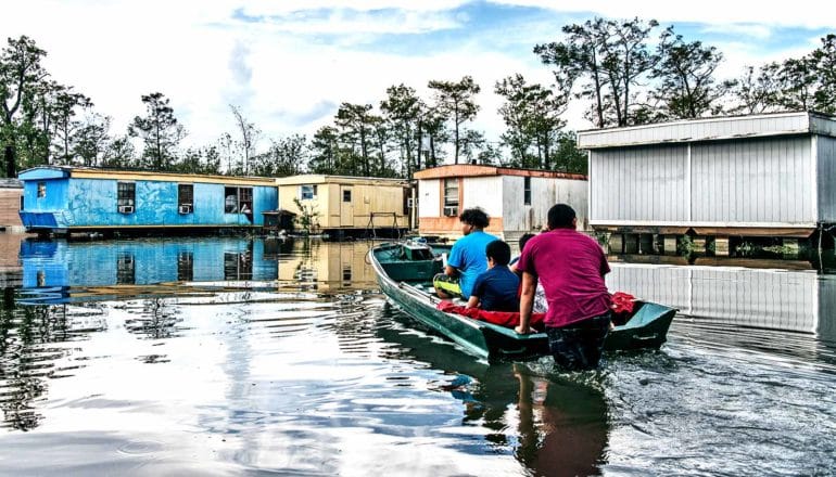 A family rides a boat through a flooded neighborhood