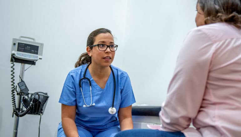 person in scrubs with stethoscope with patient