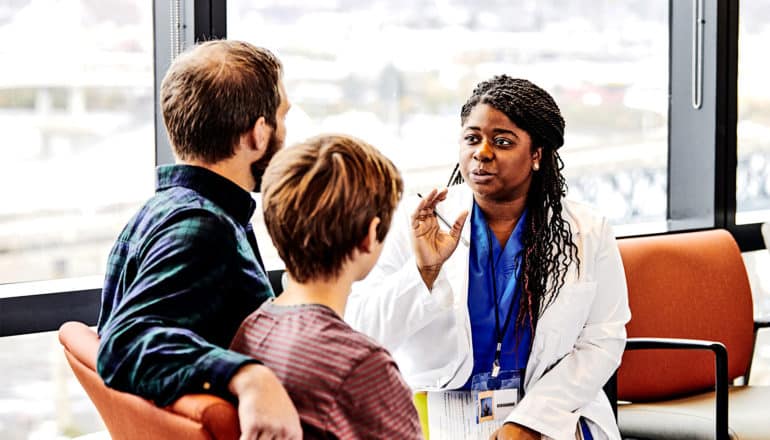 A doctor speaks with a couple sitting near a hospital window