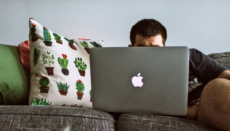 person slouches on couch with laptop