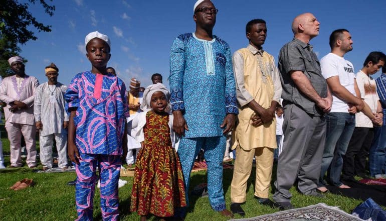 adults and children in colorful clothing stand outdoors in row