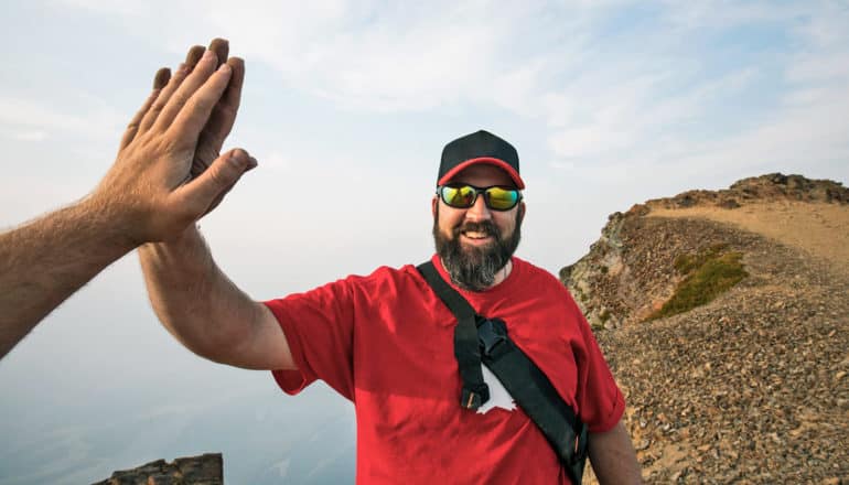 person gets high five at top of mountain