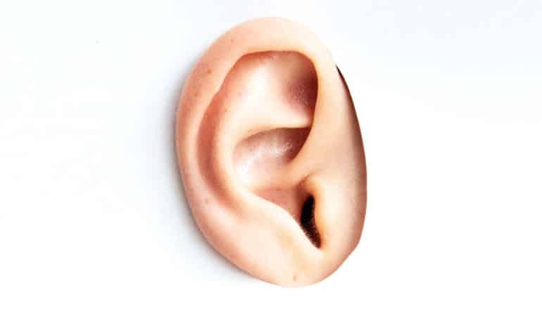 A person sticks their ear through a white piece of paper