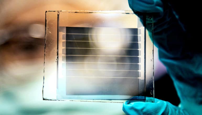 A researcher holds up a transparent solar cell