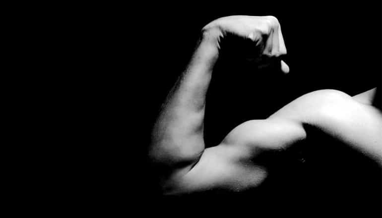 A person flexes his bicep in black and white