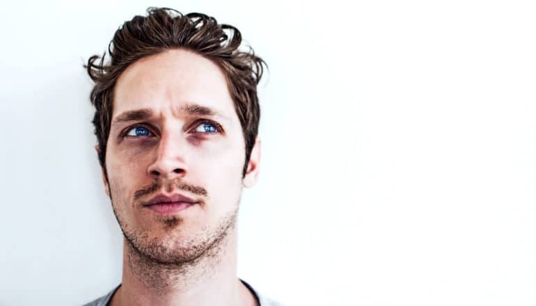 A man looks curious or lost in thought against a white background