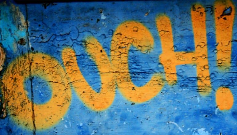 The word "Ouch!" painted in orange on blue wall