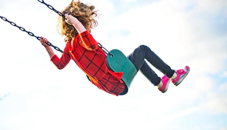 A young girl on a swing with the sky in the background