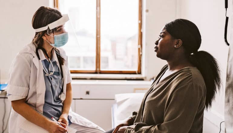 A Black woman speaks with her doctor