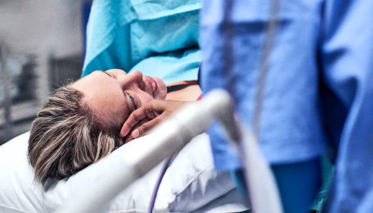 A woman in the delivery room looks up at person nearby