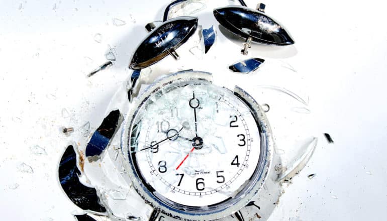 A smashed alarm clock on a white background