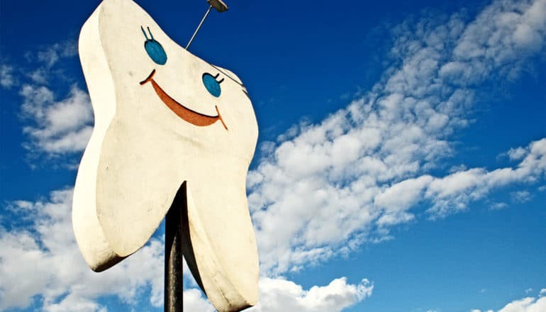 A giant tooth with a smiling face advertises a dentist