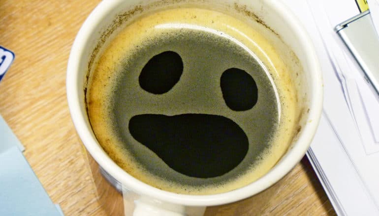 upset face on surface of coffee in mug