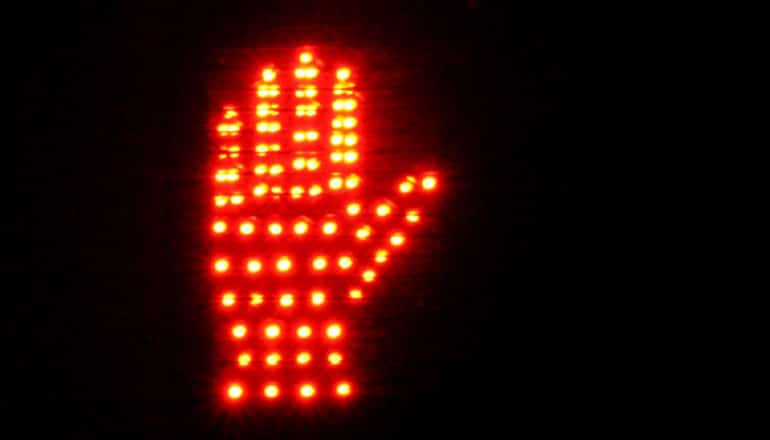 Red lights form the image of a hand on a crosswalk signal indicating "stop" or "do not walk"