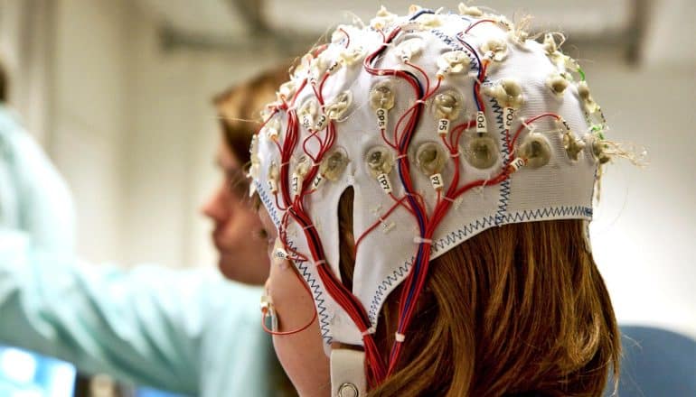 A young girl wears and eeg cap with electrodes and wires running from it