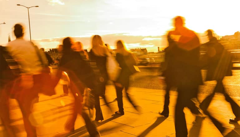 People walk on a sidewalk with orange light covering everything