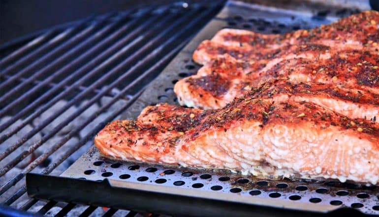 Salmon covered in spices cooks on a grill