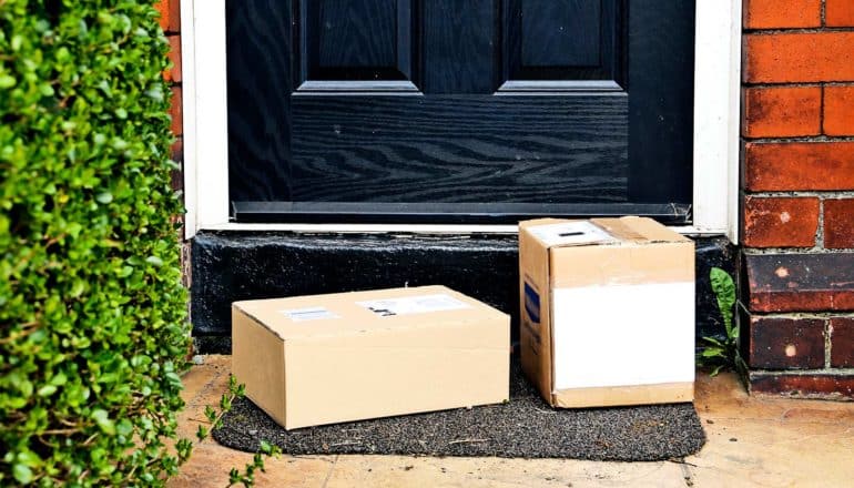 Packages sit on a doorstep in front of a black door