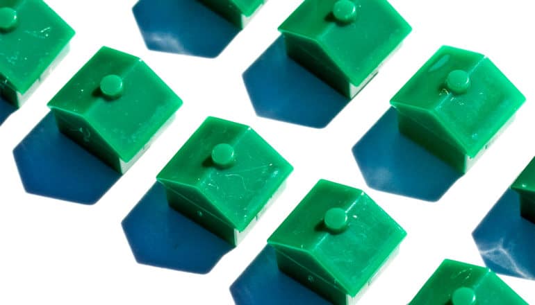 Small green toy houses lined up in rows on a white background