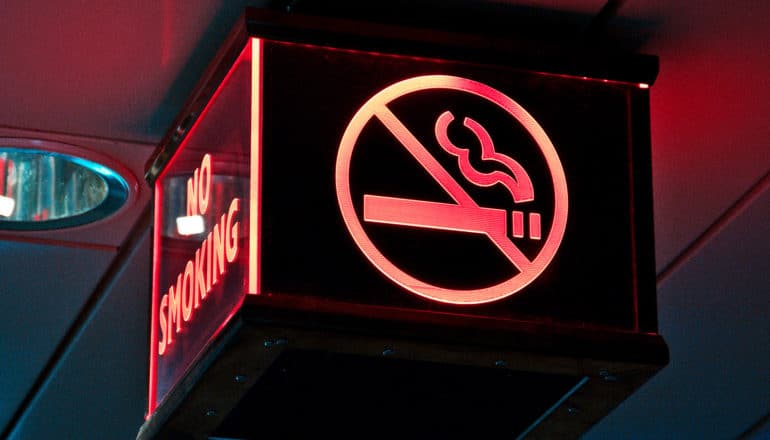 A no-smoking sign on a ceiling lighted in red