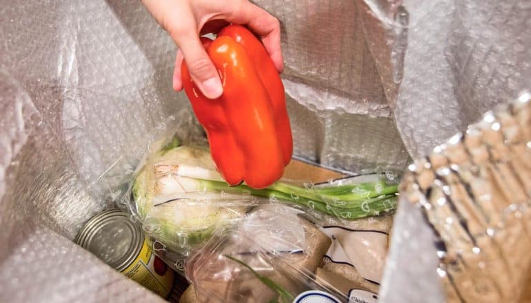 hand pulls red pepper from box of packaged ingredients